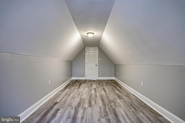 additional living space featuring hardwood / wood-style flooring and vaulted ceiling