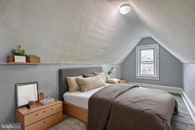 bedroom featuring light hardwood / wood-style floors and lofted ceiling