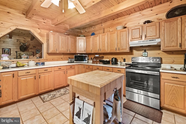 kitchen with beam ceiling, stainless steel appliances, wooden walls, and light tile patterned flooring