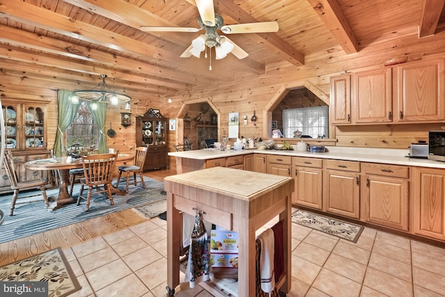 kitchen with kitchen peninsula, ceiling fan, beamed ceiling, and light tile patterned floors