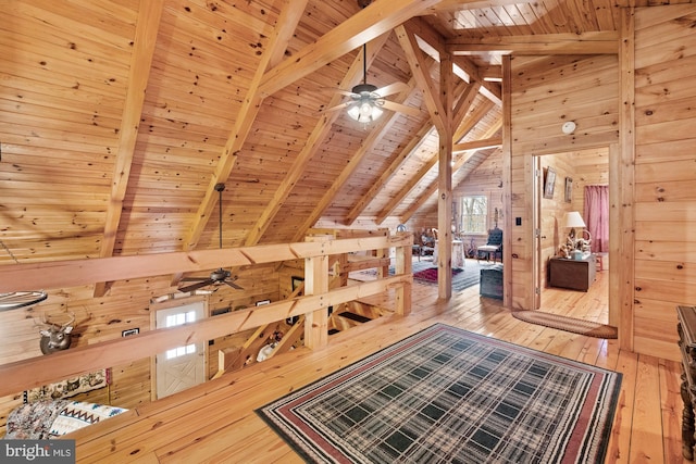 bonus room with lofted ceiling with beams, wooden walls, ceiling fan, wood-type flooring, and wood ceiling