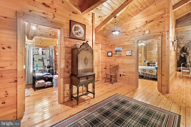 hall with light hardwood / wood-style floors, vaulted ceiling with beams, wood walls, and wooden ceiling