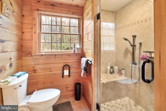 bathroom featuring wood walls, toilet, a healthy amount of sunlight, and a shower with door