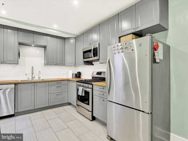 kitchen with gray cabinets, sink, stainless steel appliances, and wooden counters