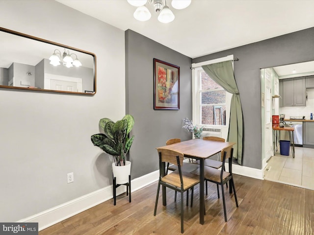 dining space with wood-type flooring and an inviting chandelier