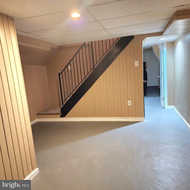 basement with wooden walls and a drop ceiling