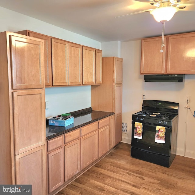 kitchen with black gas range, dark stone counters, and light wood-type flooring