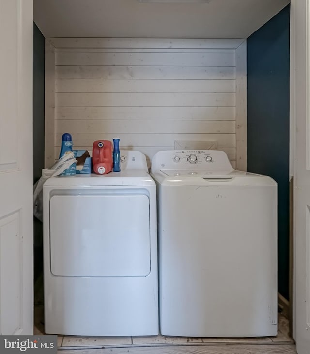 washroom with separate washer and dryer and wooden walls