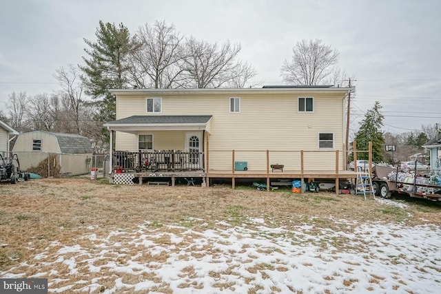 snow covered back of property featuring a storage unit and a wooden deck