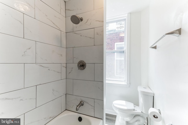 bathroom featuring toilet and tiled shower / bath