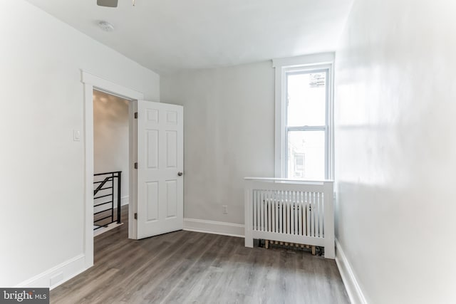 unfurnished bedroom featuring radiator heating unit, hardwood / wood-style flooring, and a nursery area