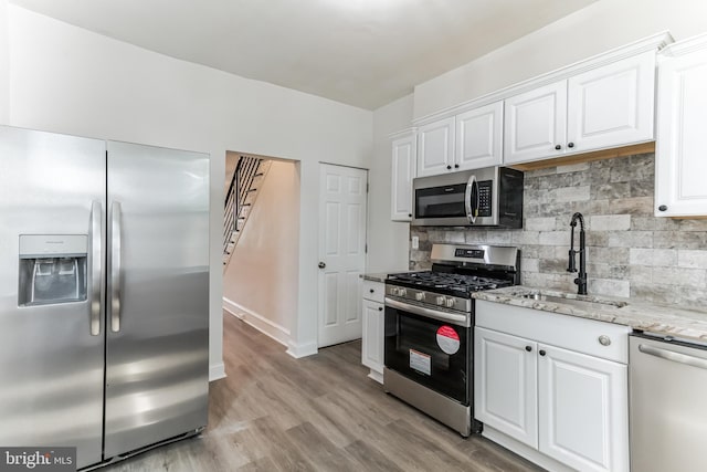 kitchen featuring decorative backsplash, stainless steel appliances, white cabinetry, and sink