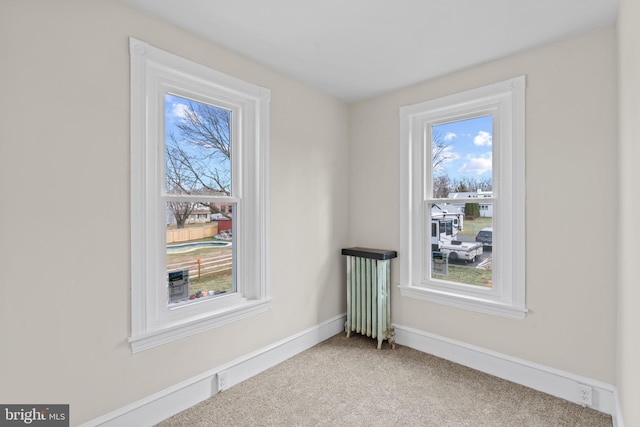 spare room featuring light carpet and radiator