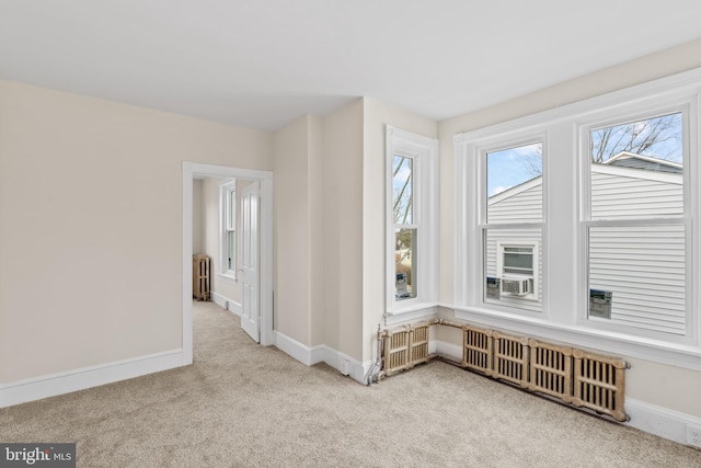 unfurnished room featuring light carpet and radiator heating unit