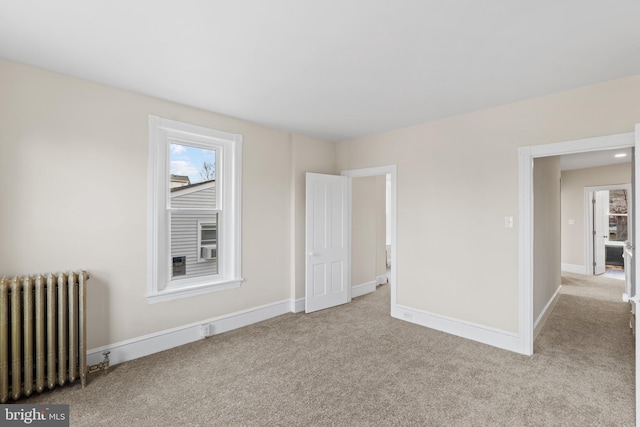 spare room with radiator heating unit and light colored carpet