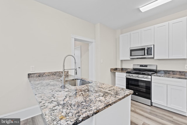 kitchen featuring light stone counters, sink, white cabinets, and stainless steel appliances