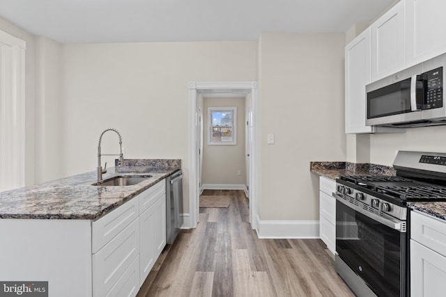 kitchen featuring white cabinetry, sink, dark stone counters, and appliances with stainless steel finishes