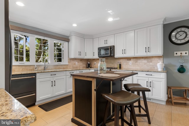 kitchen with white cabinets, appliances with stainless steel finishes, light stone countertops, and sink