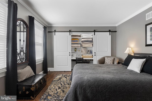 bedroom featuring a barn door, dark hardwood / wood-style floors, and ornamental molding