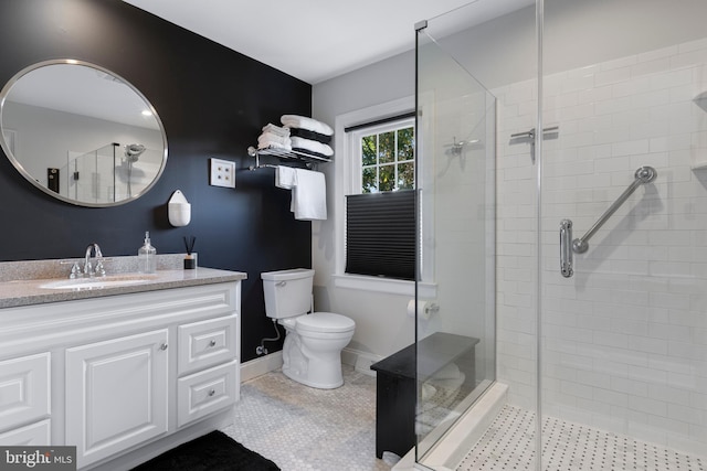 bathroom featuring toilet, vanity, tile patterned floors, and a shower with shower door