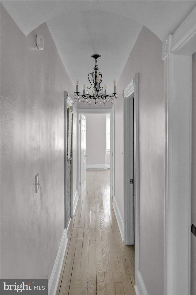 hall with an inviting chandelier and light wood-type flooring