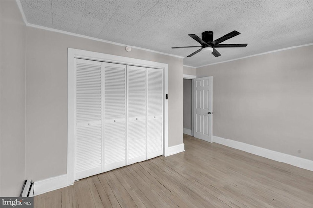 unfurnished bedroom featuring ceiling fan, light wood-type flooring, ornamental molding, baseboard heating, and a closet