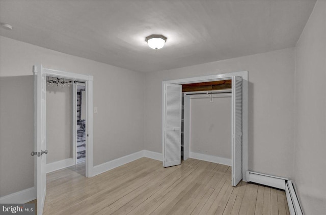 unfurnished bedroom featuring light hardwood / wood-style floors, a baseboard heating unit, and a closet