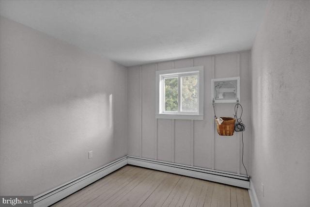 unfurnished room featuring light hardwood / wood-style flooring and a baseboard heating unit