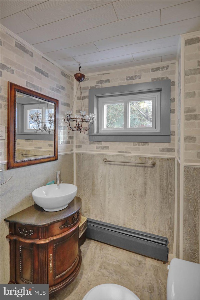 bathroom with wood ceiling, brick wall, vanity, a chandelier, and toilet