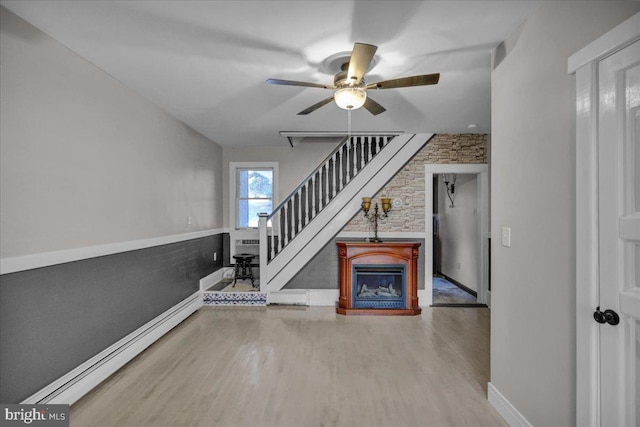 unfurnished living room featuring ceiling fan, a baseboard radiator, brick wall, and hardwood / wood-style flooring