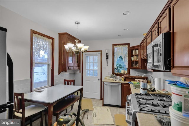 kitchen with a healthy amount of sunlight, pendant lighting, stainless steel appliances, and a notable chandelier