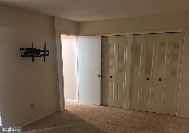 unfurnished bedroom featuring light carpet and multiple closets