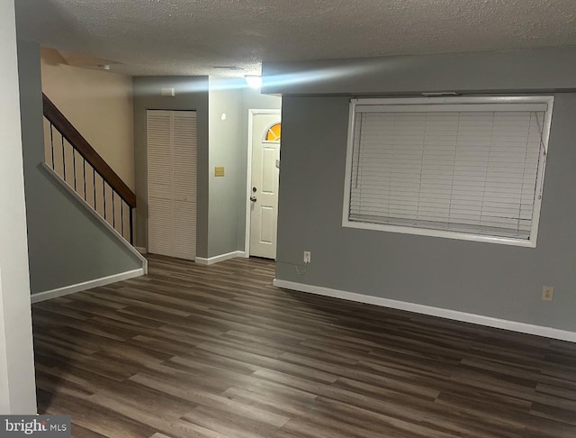 spare room with a textured ceiling and dark hardwood / wood-style flooring