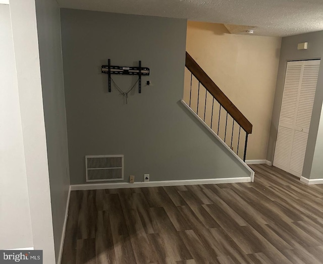 stairway with wood-type flooring and a textured ceiling