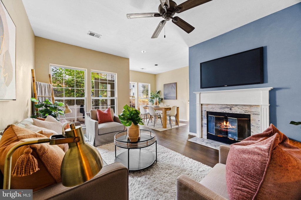 living room featuring ceiling fan, wood-type flooring, and a high end fireplace