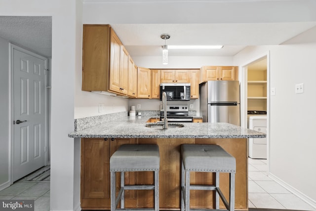 kitchen featuring a kitchen breakfast bar, light stone counters, light tile patterned floors, and appliances with stainless steel finishes