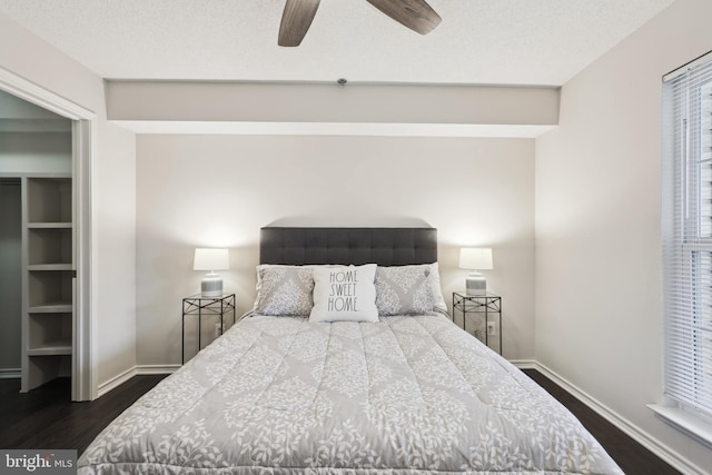 bedroom with a textured ceiling, ceiling fan, and dark wood-type flooring