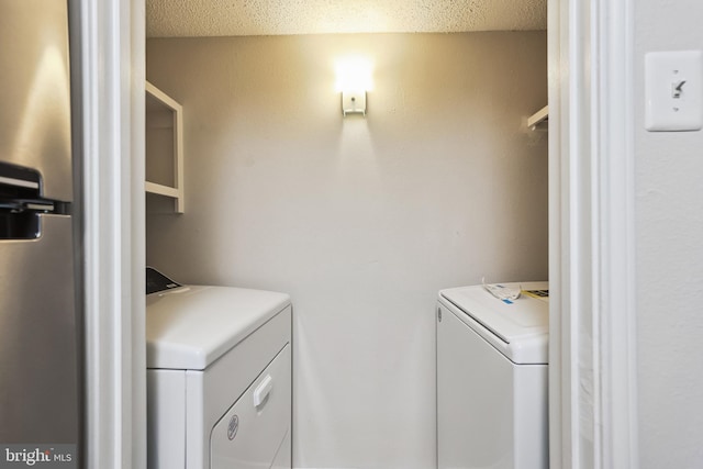 clothes washing area with separate washer and dryer and a textured ceiling