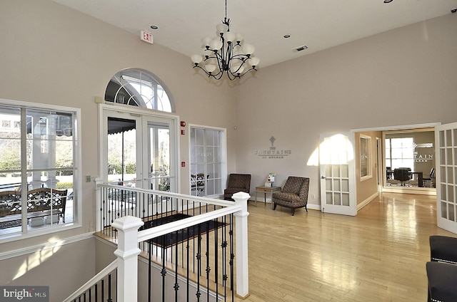 corridor featuring hardwood / wood-style floors, a notable chandelier, a high ceiling, and french doors