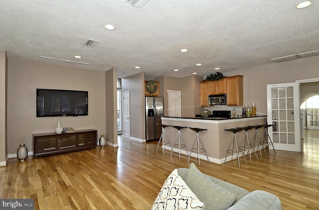 kitchen with a kitchen breakfast bar, kitchen peninsula, stainless steel fridge, and a textured ceiling