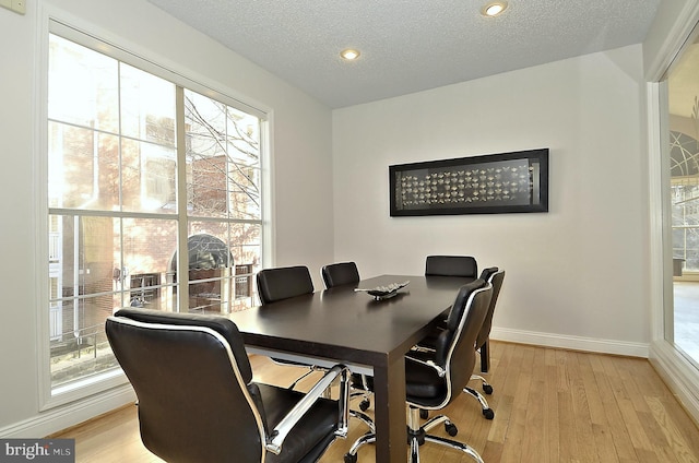 home office with light hardwood / wood-style flooring and a textured ceiling