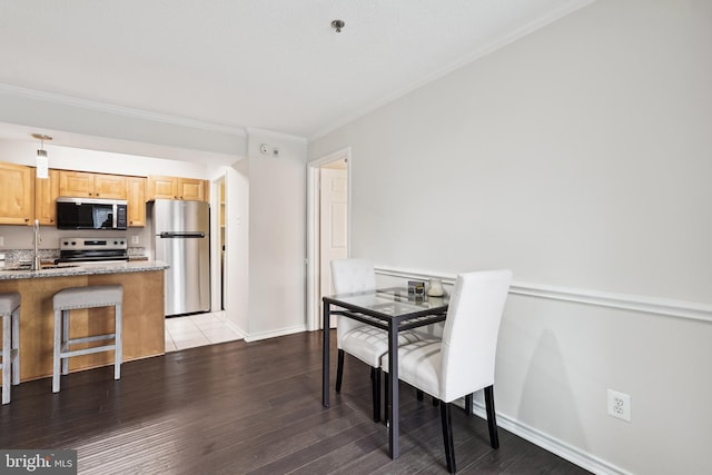 dining space featuring light hardwood / wood-style floors, crown molding, and sink