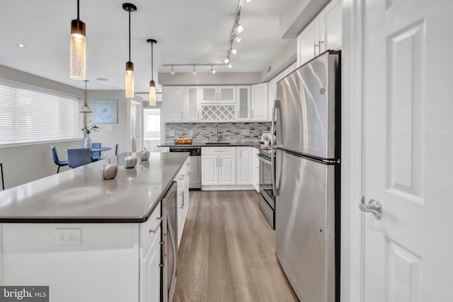 kitchen featuring white cabinets, decorative light fixtures, and stainless steel appliances