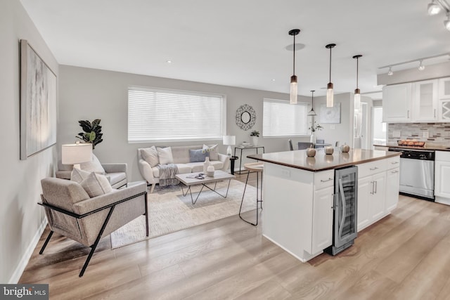 kitchen with white cabinetry, a center island, hanging light fixtures, beverage cooler, and stainless steel dishwasher