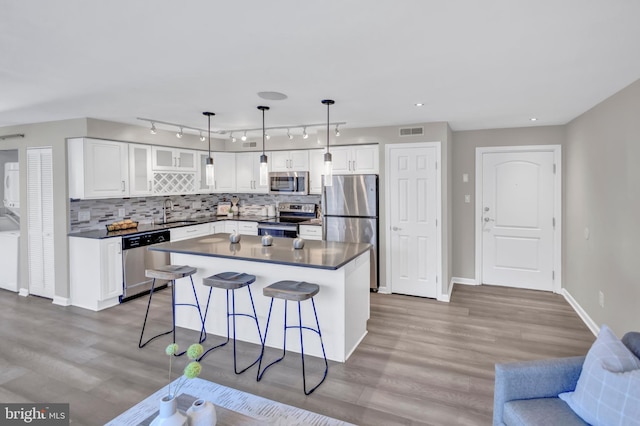 kitchen with sink, white cabinetry, stainless steel appliances, and hanging light fixtures