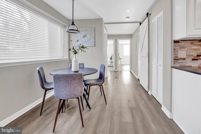 dining room with a barn door, light hardwood / wood-style floors, and a healthy amount of sunlight