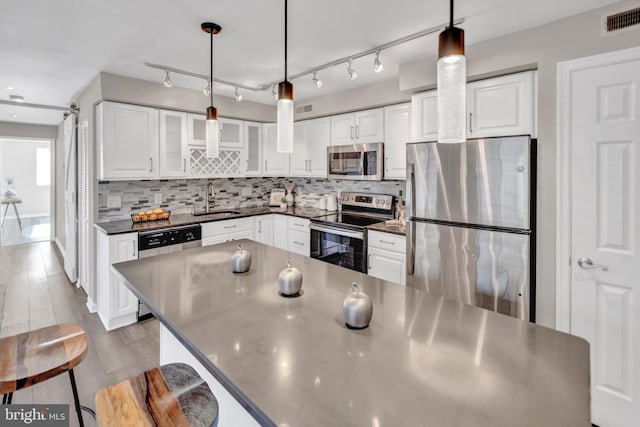 kitchen featuring sink, a barn door, decorative light fixtures, white cabinetry, and stainless steel appliances