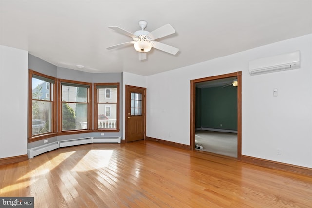 spare room featuring a wall mounted air conditioner, ceiling fan, light hardwood / wood-style floors, and baseboard heating