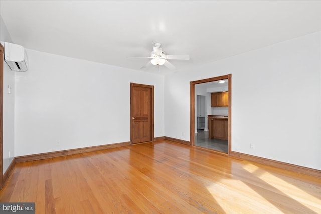 empty room featuring an AC wall unit, ceiling fan, and light hardwood / wood-style floors