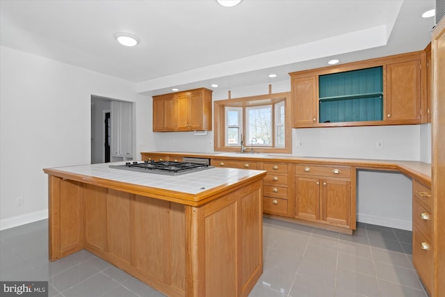 kitchen with tile counters, a center island, sink, stainless steel gas cooktop, and light tile patterned flooring